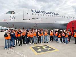 Schüler und Lehrer in Warnwesten vor einem Passagierflugzeug auf dem Stuttgarter Flughafen