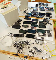 Viele Smartphones auf einem Tisch mit Sammelbehältern